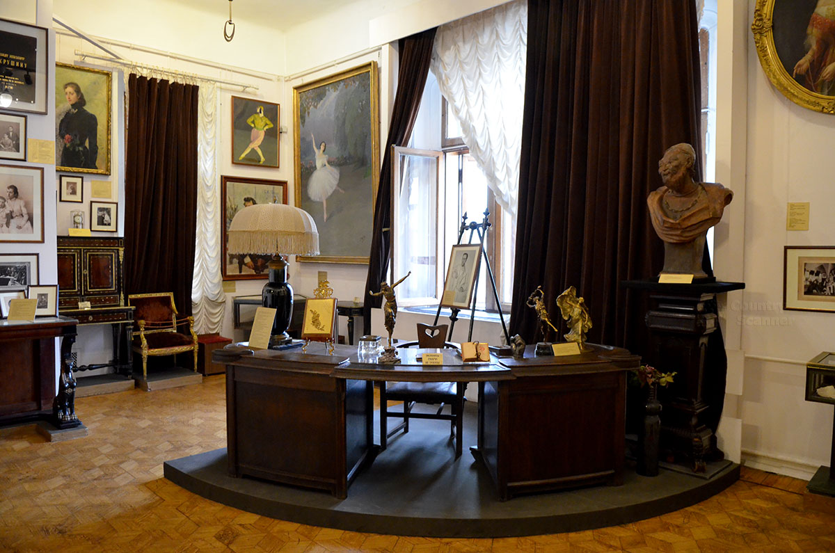 Вид на письменный стол хозяина и предметы коллекционирования в кабинете руководителя музея Бахрушина. Многочисленные портреты актеров и актрис при исполнении ролей и в произвольной обстановке.