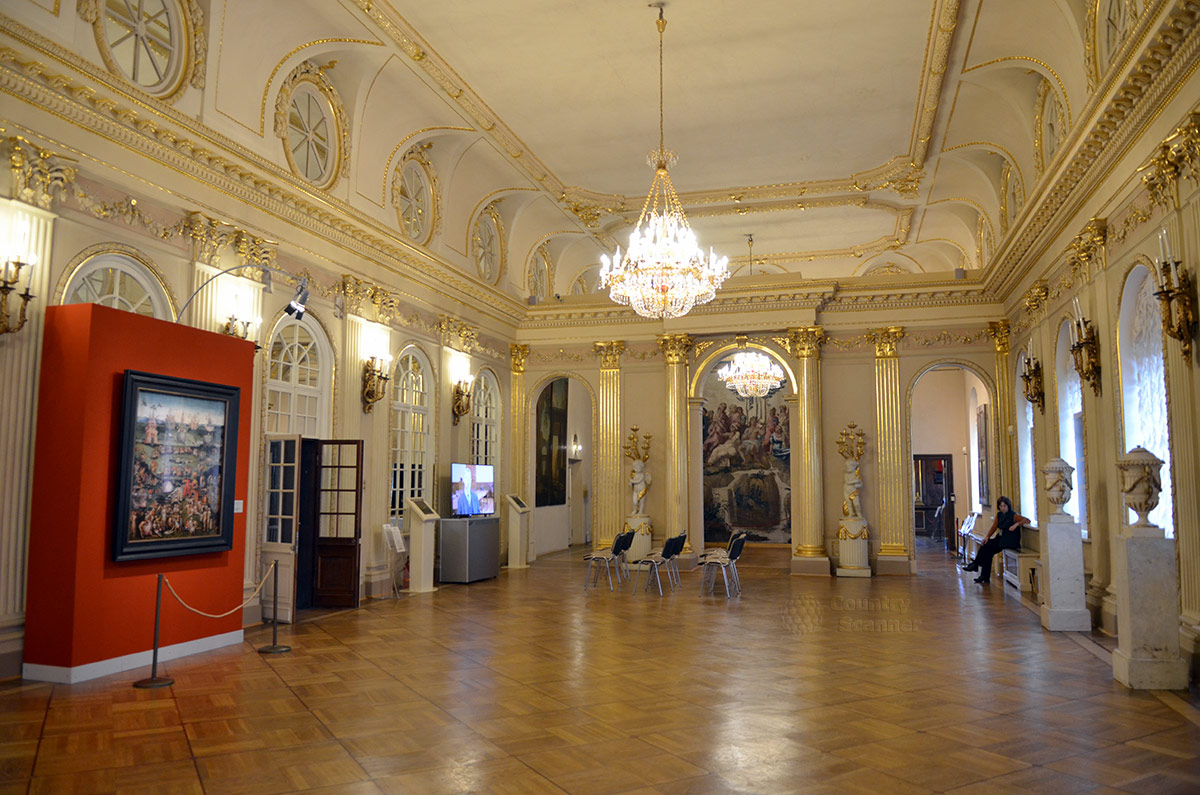 Вид на другую оконечность Большого зала дворца Меншикова демонстрирует его убранство. Колонны и пилястры с позолоченными элементами дополняются скульптурными подсвечниками и картинами.