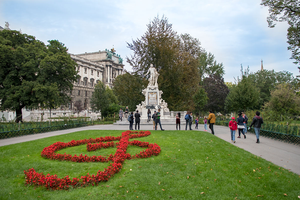 Огромный скрипичный ключ из распустившихся цветов на зеленом газоне возобновляется каждый год, подчеркивая привлекательность памятника Моцарту.